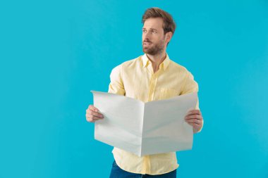 Düşünceli, sıradan bir adam elinde gazete tutuyor ve başka tarafa bakıyor.