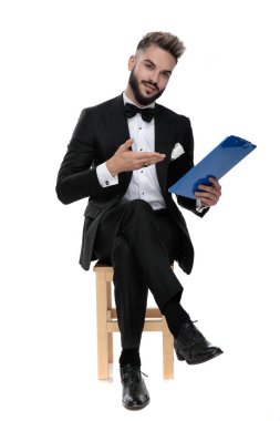 businessman sitting and presenting something on clipboard happy