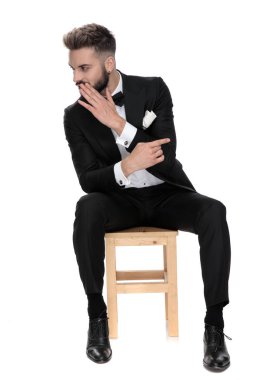 businessman sitting while pointing to a side whispering the othe