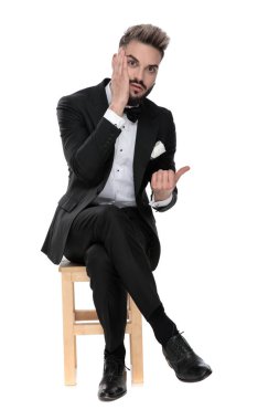 businessman sitting and touching face while pointing aside worri