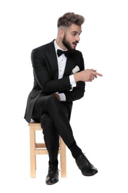 businessman sitting and pointing to a side shocked