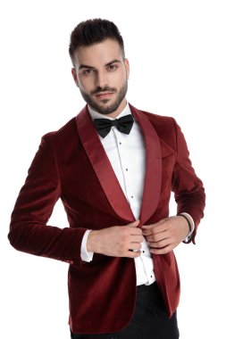 sexy young man in red velvet tuxedo fixing coat