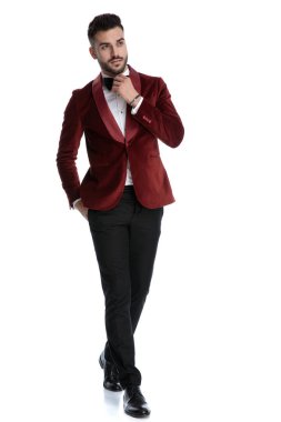 sexy young model in tuxedo walking and fixing bowtie