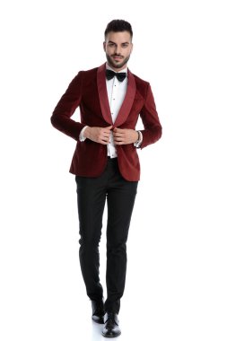 smiling young man walking and adjusting coat