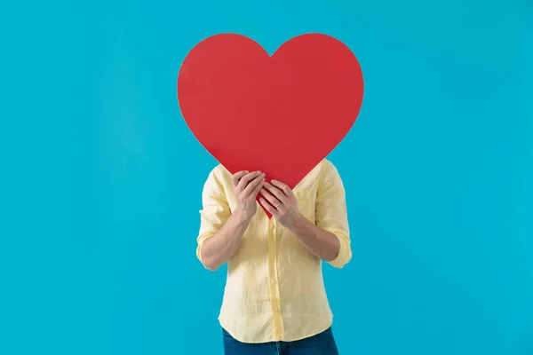 Young casual man hiding his face behind a heart shape — Stock Photo, Image