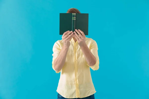 Jonge casual man verbergt zijn gezicht achter een boek — Stockfoto
