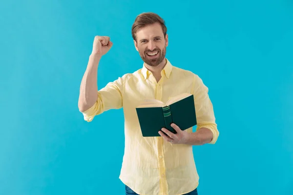 Allegro uomo casual che ride e festeggia con un libro — Foto Stock