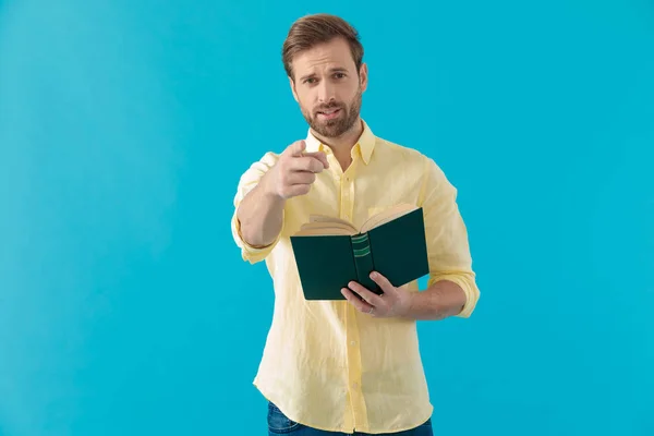 Vertrauter lässiger Mann zeigt, hält ein Buch in der Hand und lächelt — Stockfoto