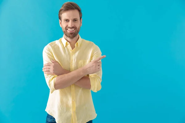 Casual man pointing to the side with his hands crossed — Stock Photo, Image