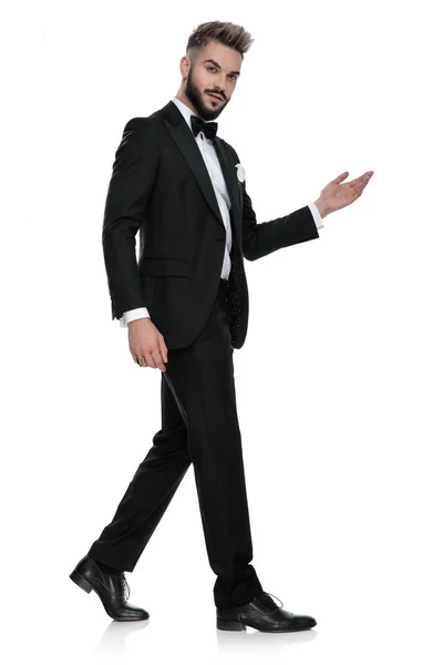 Young businessman walking while presenting something — Stockfoto