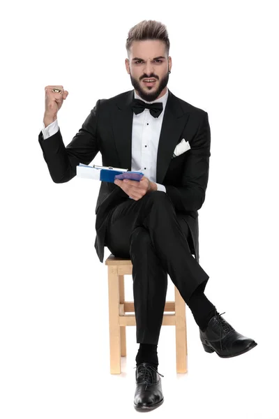 Businessman sitting and holding clipboard while aggressive raisi — Stockfoto