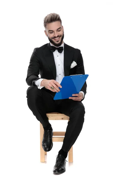 Hombre de negocios sentado y mirando hacia abajo al portapapeles feliz — Foto de Stock