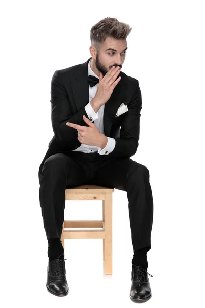 Hombre de negocios sentado mientras chismorrea a alguien y señala hacia —  Fotos de Stock