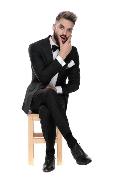 Geschäftsmann sitzt und reibt sich schockiert das Gesicht — Stockfoto