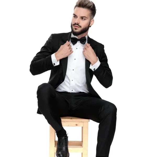 Businessman sitting and fixing jacket while looking aside seriou — Stockfoto