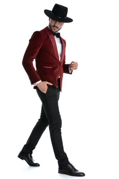 Sexy young man in red velvet tuxedo walking and looking to side — Stok fotoğraf