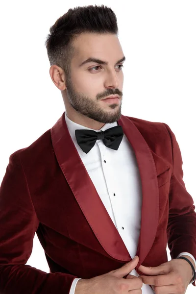 Sexy young man in red velvet tuxedo adjusting coat — Stockfoto