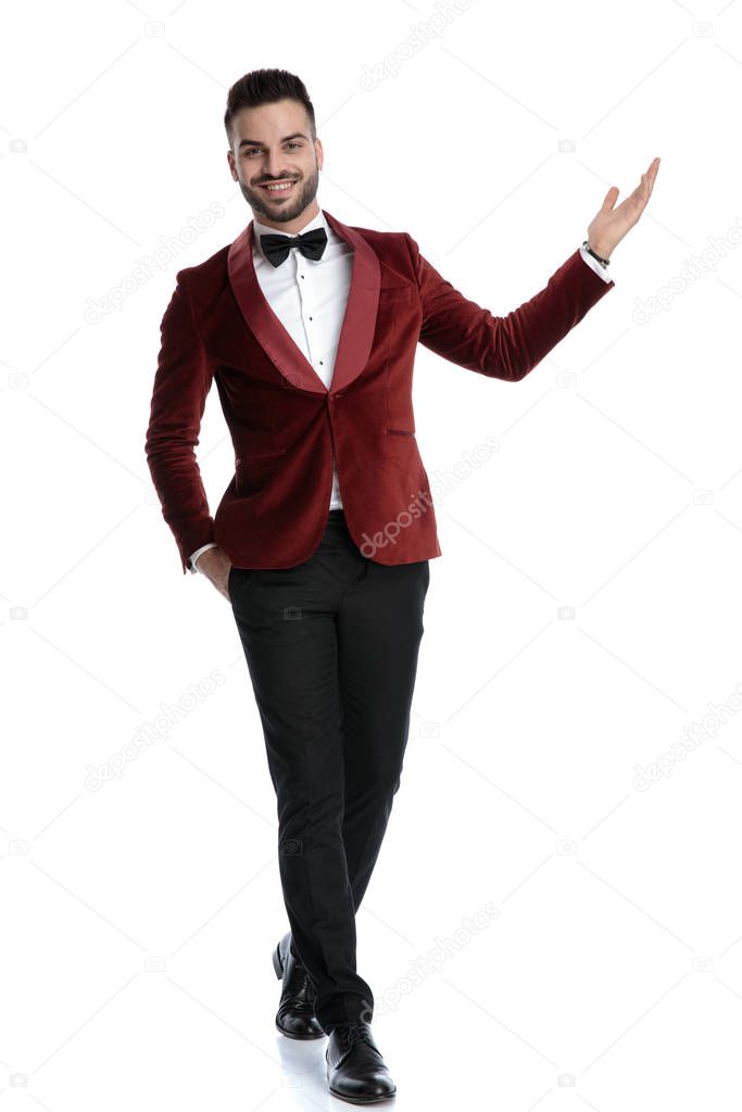 happy young model in tuxedo smiling and presenting to side