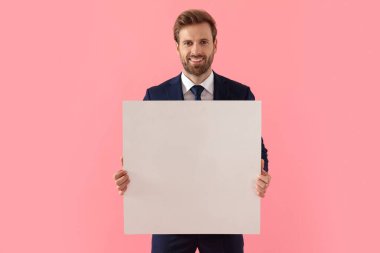 Mutlu iş adamı elinde boş bir ilan panosu tutuyor ve gülümsüyor.
