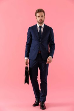 Elinde evrak çantası olan sert iş adamı ileriye bakıyor.