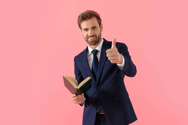 Pozitivní obchodník držící knihu a zvedající palec — Stock fotografie