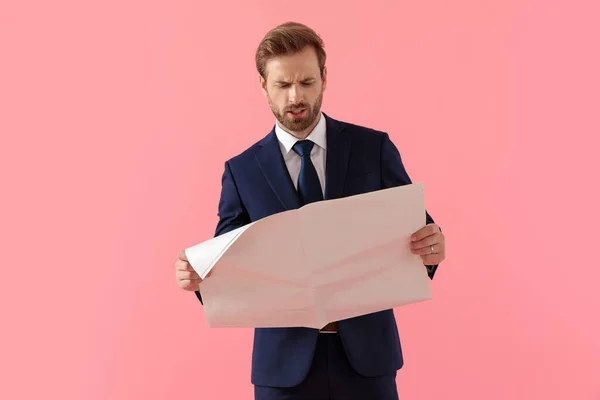 Empresario molesto leyendo un periódico y frunciendo el ceño — Foto de Stock