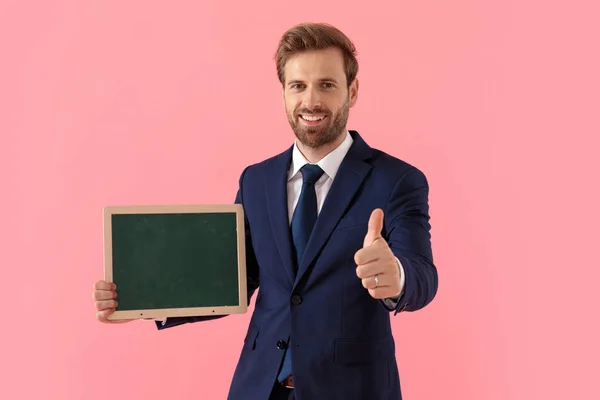 Hombre de negocios positivo sosteniendo una pizarra y dando un pulgar hacia arriba — Foto de Stock