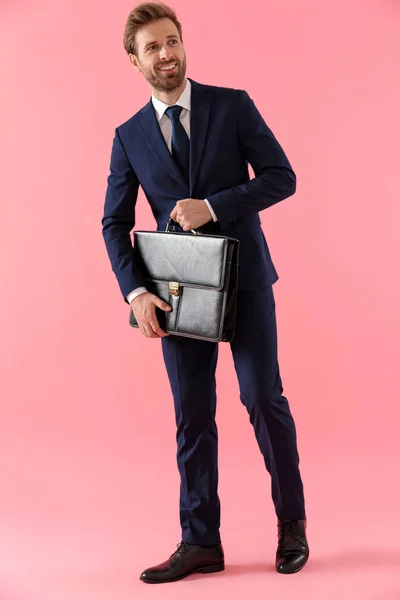 Hombre de negocios alegre sosteniendo un maletín y sonriendo — Foto de Stock