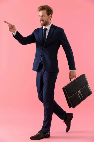 Uomo d'affari fiducioso in possesso di una valigetta e indicando — Foto Stock