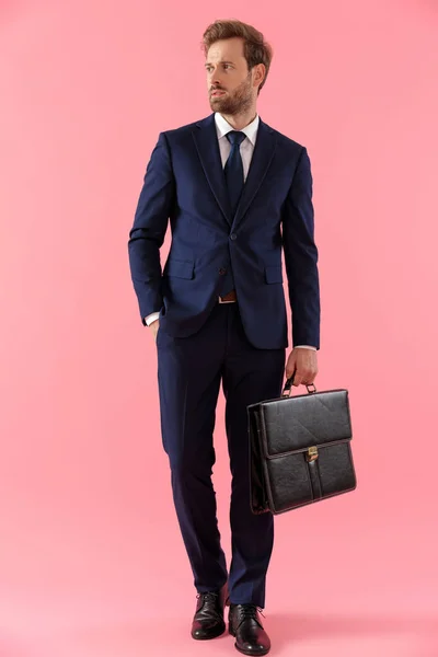 Pensive businessman holding a briefcase and looking away — Stock fotografie