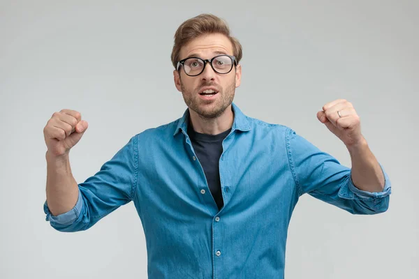 Jong casual slim guy houden vuisten in de lucht en vieren — Stockfoto