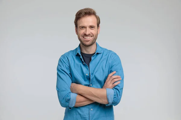 Enthusiastic young casual man crossing arms and smiling — Stock Photo, Image