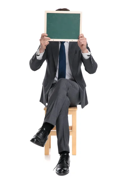 Елегантний бізнесмен покриває обличчя зеленою дошкою — стокове фото