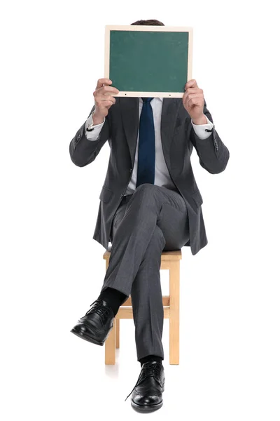 Elegante hombre de negocios que cubre la cara con tablero verde — Foto de Stock