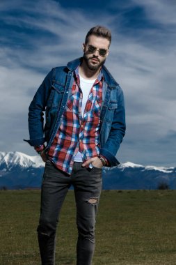 Kendine güvenen bir adam kot ceket giyerken ileriye bakar.