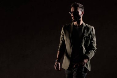 Havalı traşsız adam stüdyoda moda ışığında yürüyor.