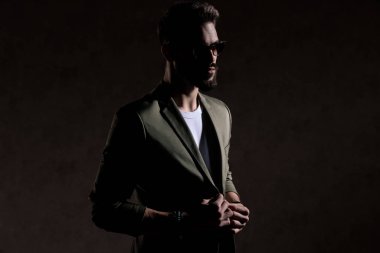 Seksi manken, yeşil ceketi moda ışığında ayarlıyor.