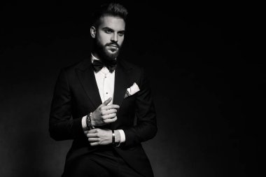 İş adamı oturuyor ve kollarını düzeltiyor.