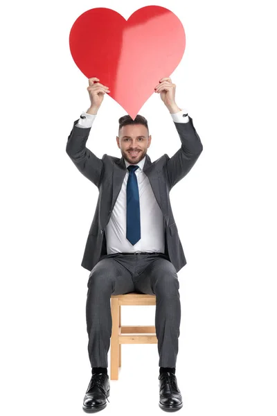 Joven feliz sosteniendo gran corazón rojo por encima de la cabeza — Foto de Stock