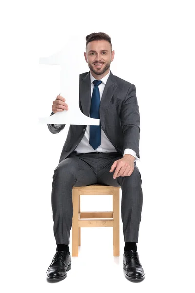 Молодий бізнесмен тримає знак номер один і посміхається — стокове фото