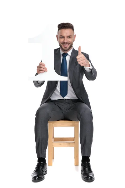 Happy young businessman holding number one sign — Stock Photo, Image