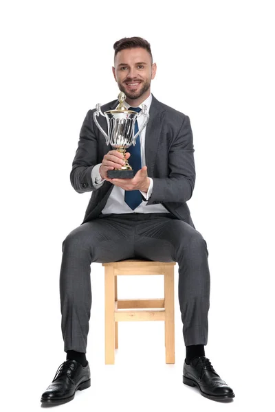 Joven empresario sosteniendo trofeo y sonriendo — Foto de Stock