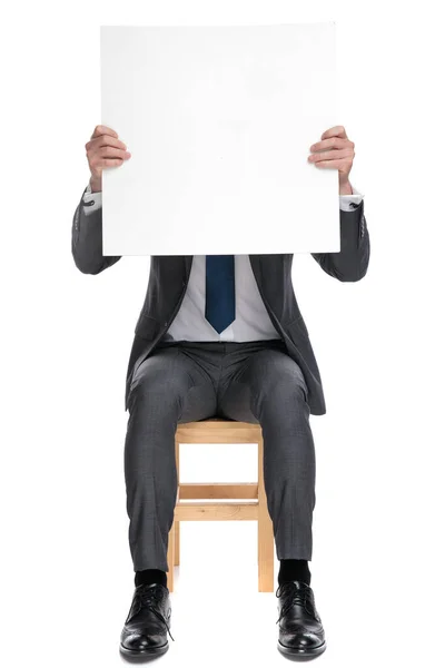 Mladý podnikatel zakrývající tvář s prázdnou tabulí — Stock fotografie