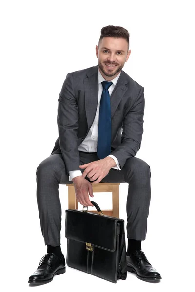 Young businessman holding suitcase and smiling — Stock Photo, Image