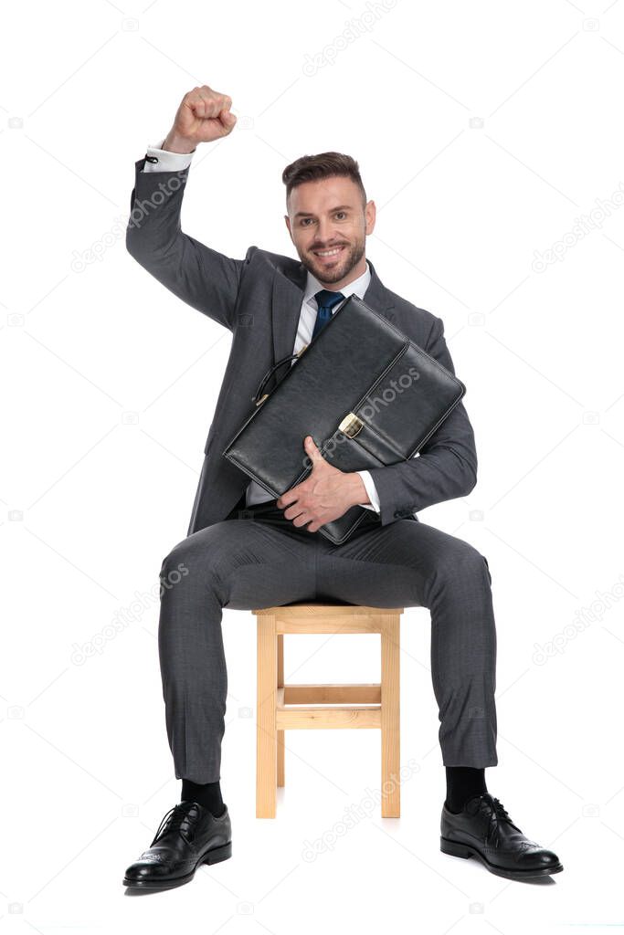 happy young businessman celebrating victory and holding suitcase