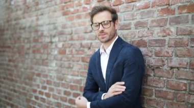 Elleri çapraz duran endişeli genç işadamı, duvara yaslanırken gülümsemeye başlıyor.