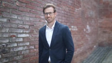 Gözlüklü yakışıklı genç adam eski bir kasabanın sokağında el ele duruyor.