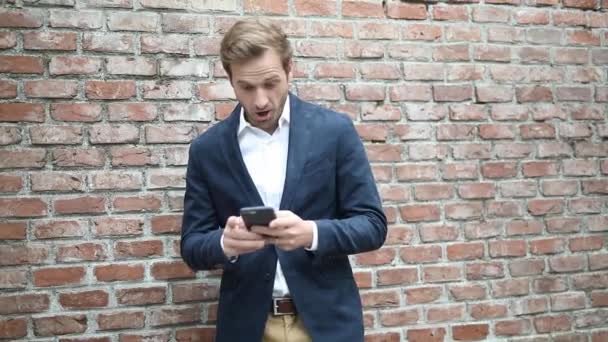 Opgewonden jonge slimme casual man ontvangt zeer goed nieuws op zijn smartphone en celbrating succes — Stockvideo