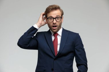 businessman standing and scratching his head shocked