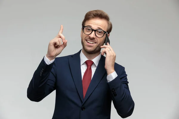 Businessman talking on the phone while pointing up — 图库照片